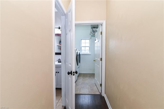 hall featuring a sink, washer / clothes dryer, and baseboards