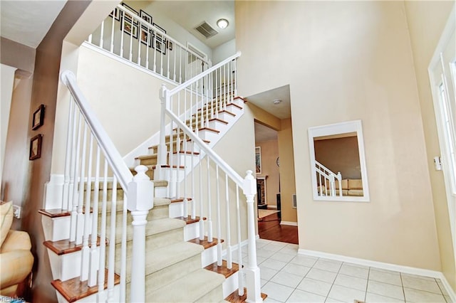 staircase with visible vents, a high ceiling, tile patterned flooring, and baseboards