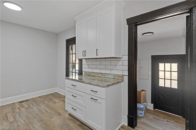 kitchen featuring tasteful backsplash, light wood finished floors, visible vents, and white cabinetry