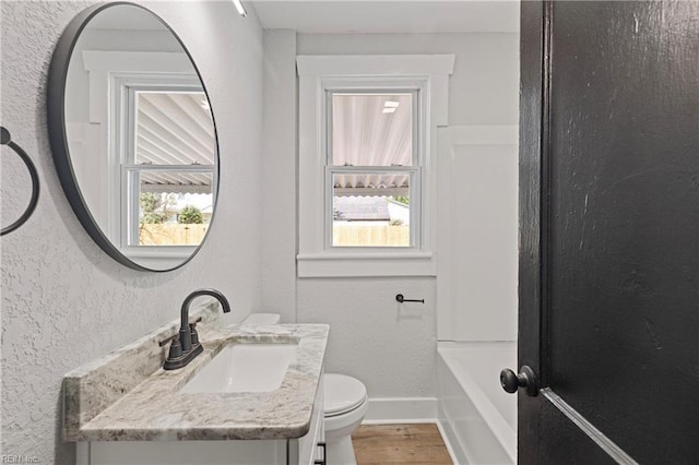 bathroom with toilet, a wealth of natural light, and a textured wall