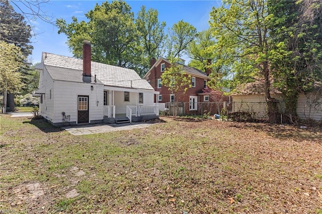 rear view of property featuring a chimney, fence, and a lawn