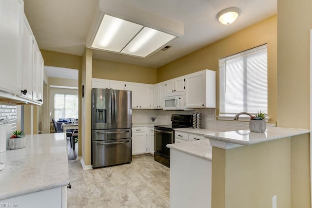 kitchen featuring stainless steel refrigerator with ice dispenser, a peninsula, white microwave, white cabinetry, and black range with electric stovetop