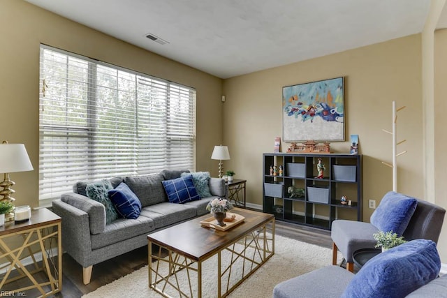 living room with visible vents, baseboards, and wood finished floors