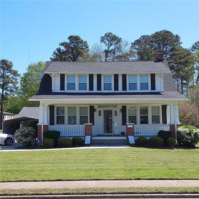 view of front of house with brick siding, a porch, a chimney, and a front lawn