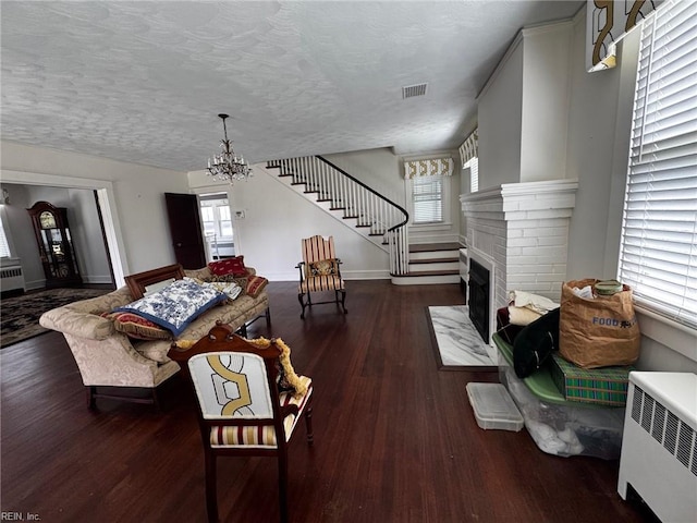 living area with radiator, wood finished floors, visible vents, and a wealth of natural light