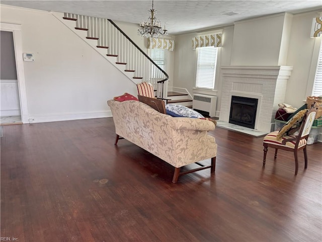 living area with a notable chandelier, baseboards, radiator heating unit, stairs, and wood finished floors