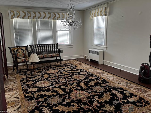 sitting room featuring baseboards, an inviting chandelier, crown molding, radiator heating unit, and wood finished floors