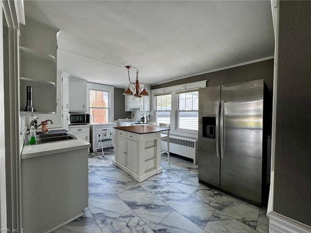 kitchen featuring radiator, white cabinetry, marble finish floor, a sink, and stainless steel fridge
