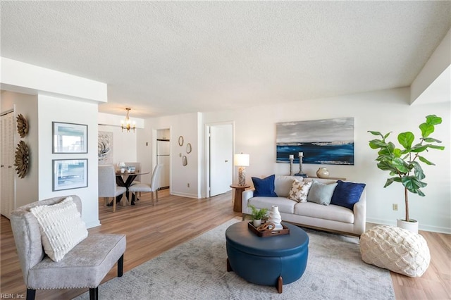 living area with a textured ceiling, wood finished floors, and a notable chandelier