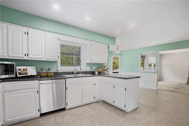 kitchen featuring a peninsula, white cabinetry, a healthy amount of sunlight, a sink, and stainless steel appliances