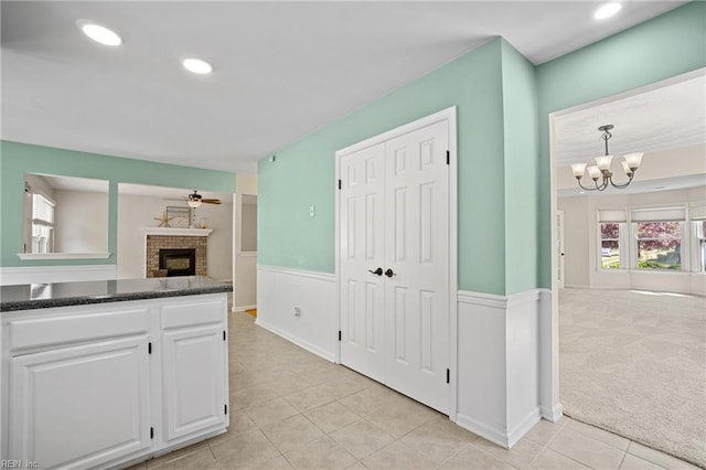 kitchen with a brick fireplace, open floor plan, dark countertops, white cabinetry, and light tile patterned flooring