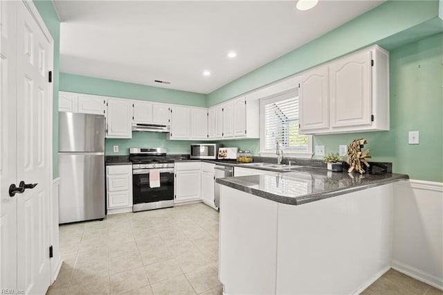 kitchen with white cabinets, a sink, appliances with stainless steel finishes, a peninsula, and under cabinet range hood