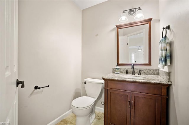 half bath with toilet, tile patterned floors, vanity, and baseboards