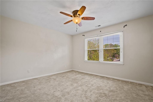 carpeted spare room featuring visible vents, baseboards, and a ceiling fan