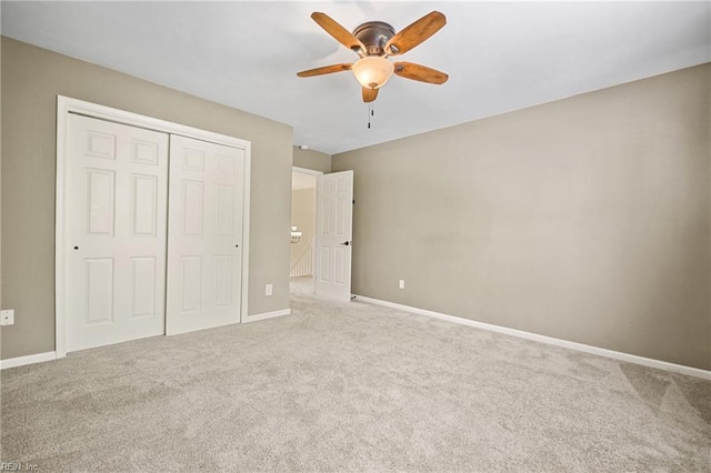 unfurnished bedroom featuring carpet, a closet, baseboards, and ceiling fan