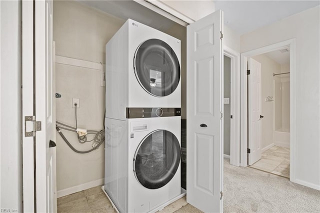 laundry area with laundry area, stacked washer and dryer, and baseboards