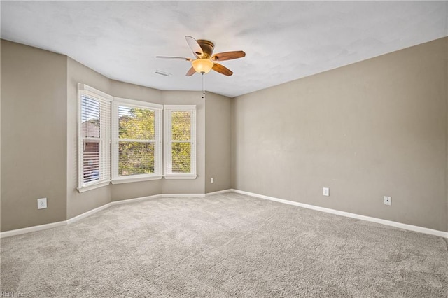 carpeted spare room featuring visible vents, ceiling fan, and baseboards