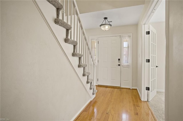 foyer with stairs, light wood-style floors, and baseboards