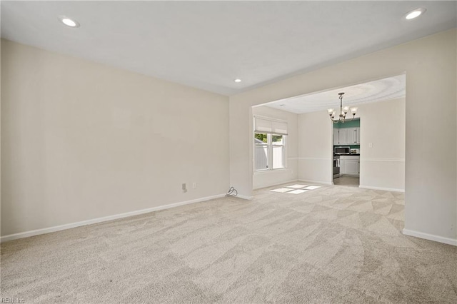 spare room featuring light colored carpet, recessed lighting, a chandelier, and baseboards