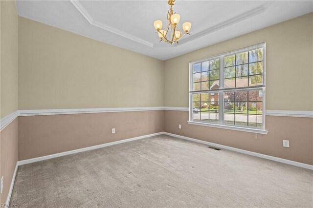 empty room with baseboards, an inviting chandelier, crown molding, a tray ceiling, and carpet flooring