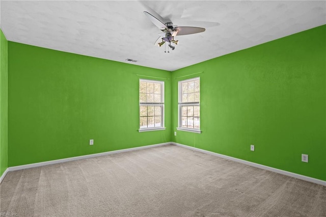 spare room featuring baseboards, carpet flooring, a textured ceiling, visible vents, and ceiling fan