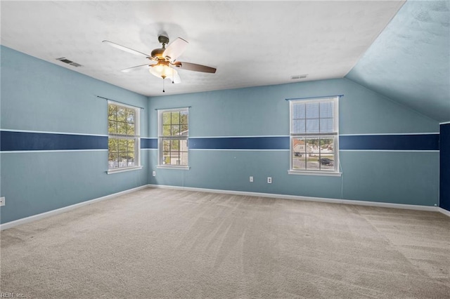 carpeted empty room featuring ceiling fan, baseboards, lofted ceiling, and visible vents