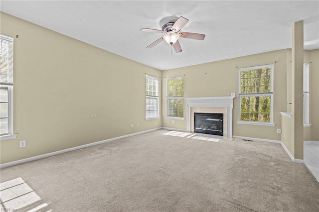 unfurnished living room featuring a fireplace with flush hearth, ceiling fan, baseboards, and carpet