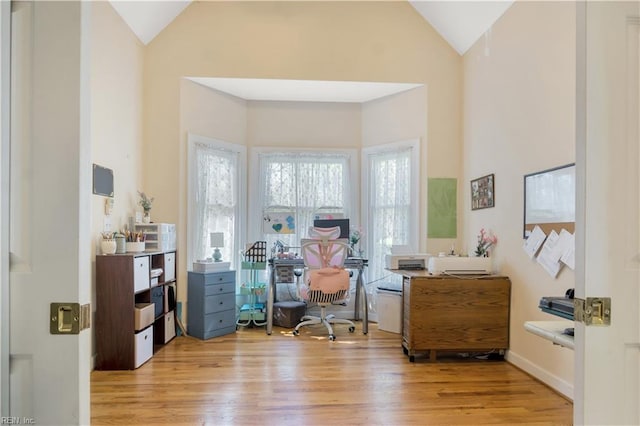 office space featuring light wood-type flooring and high vaulted ceiling