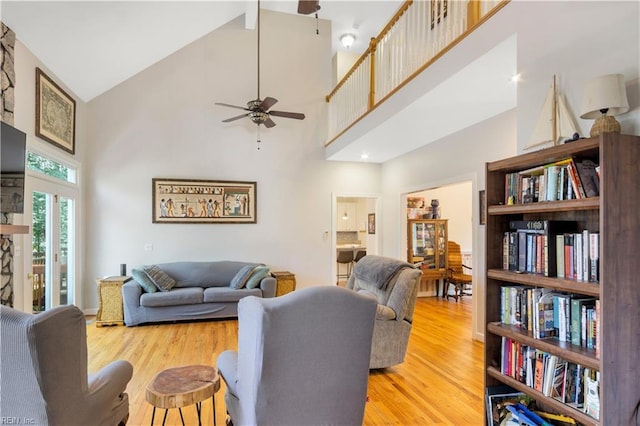 living area with high vaulted ceiling, light wood-style flooring, and a ceiling fan