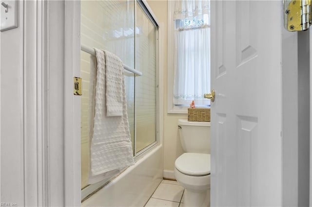 full bath with tile patterned floors, toilet, a wealth of natural light, and shower / bath combination with glass door