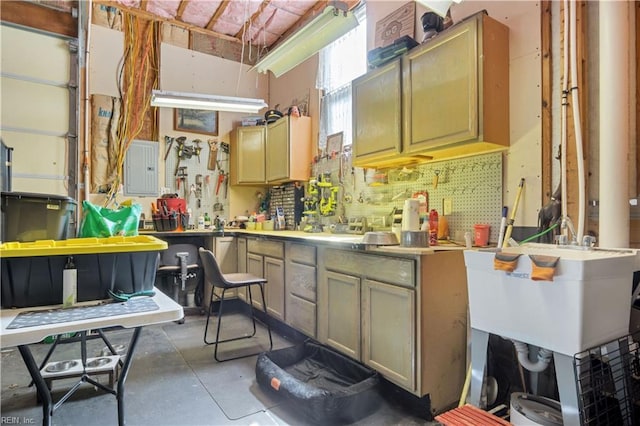 kitchen with concrete flooring, light countertops, electric panel, and a sink