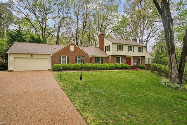 colonial inspired home featuring a front yard, brick siding, an attached garage, a chimney, and driveway