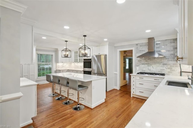 kitchen with wall chimney range hood, tasteful backsplash, a sink, and crown molding