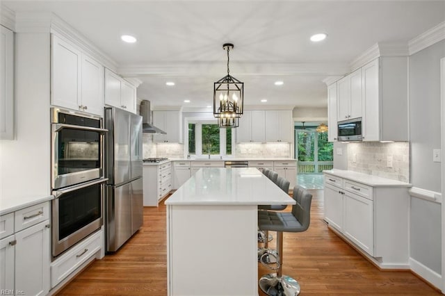 kitchen with a breakfast bar, a wealth of natural light, appliances with stainless steel finishes, and a kitchen island