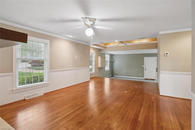 empty room with visible vents, a ceiling fan, plenty of natural light, and wood finished floors