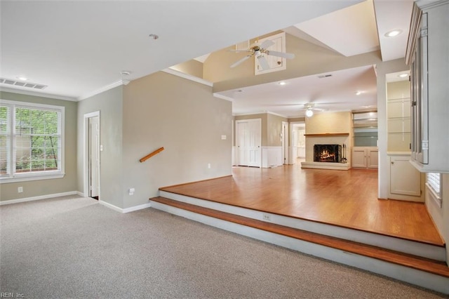 unfurnished living room with visible vents, baseboards, a ceiling fan, a fireplace, and crown molding
