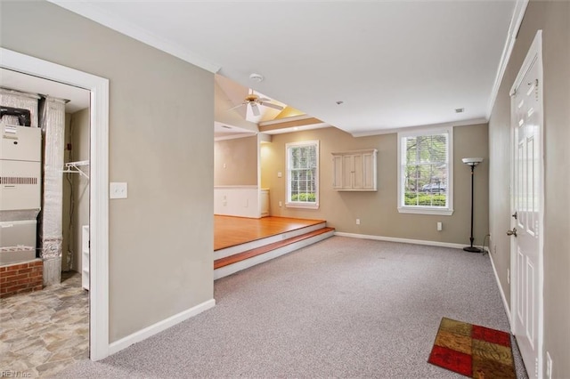 carpeted spare room featuring ornamental molding, baseboards, and ceiling fan