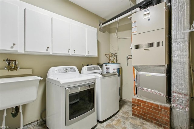 laundry room with stone finish flooring, washer and dryer, water heater, and cabinet space