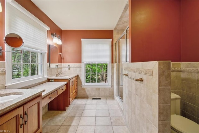 full bath featuring a stall shower, tile patterned floors, vanity, and tile walls