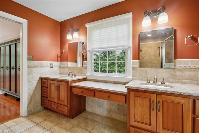 full bathroom featuring a shower stall, vanity, tile patterned flooring, and tile walls