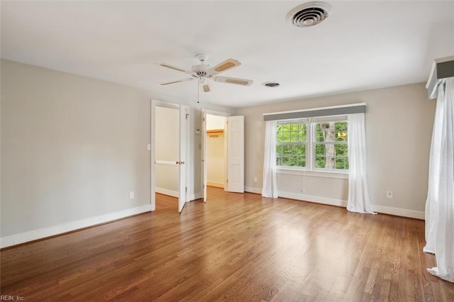 unfurnished bedroom featuring visible vents, baseboards, a ceiling fan, and wood finished floors