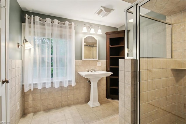 full bath featuring a stall shower, tile patterned floors, visible vents, wainscoting, and tile walls