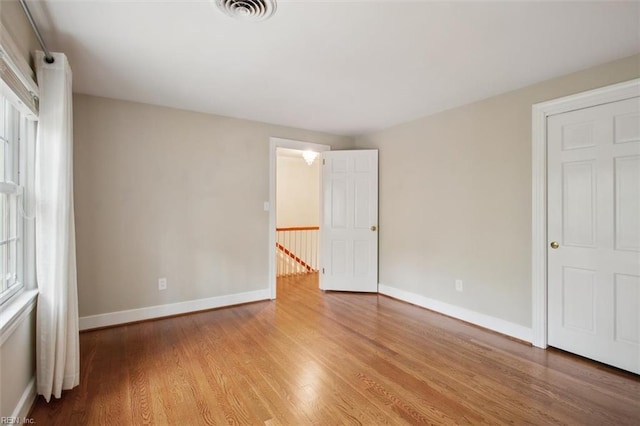 unfurnished bedroom featuring wood finished floors, baseboards, and visible vents