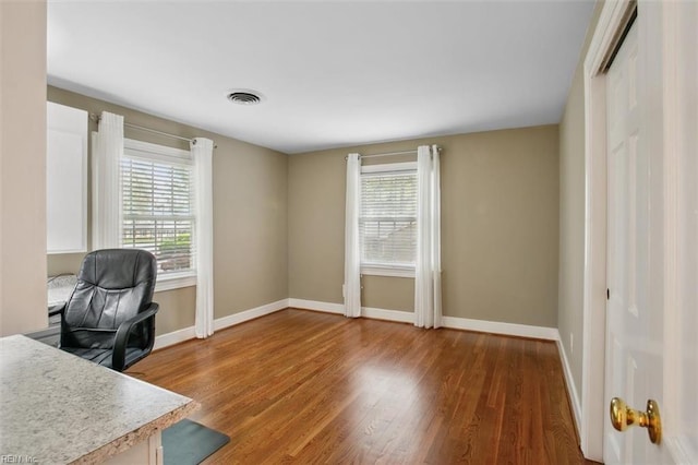 home office featuring wood finished floors, baseboards, and visible vents