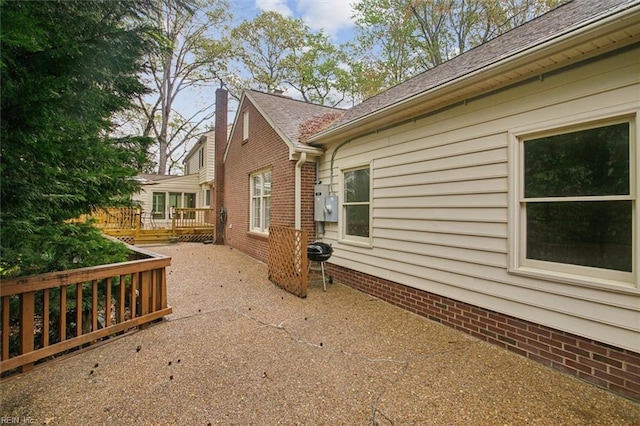view of home's exterior with a chimney, a patio area, and a deck