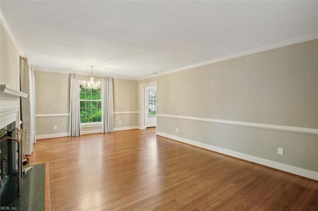 unfurnished living room featuring crown molding, wood finished floors, an inviting chandelier, and a fireplace with raised hearth