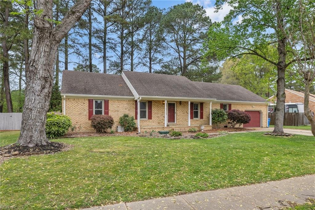 single story home featuring brick siding, a front lawn, fence, and an attached garage