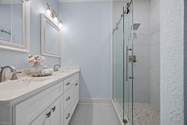 bathroom with a shower stall, a sink, tile patterned flooring, and baseboards