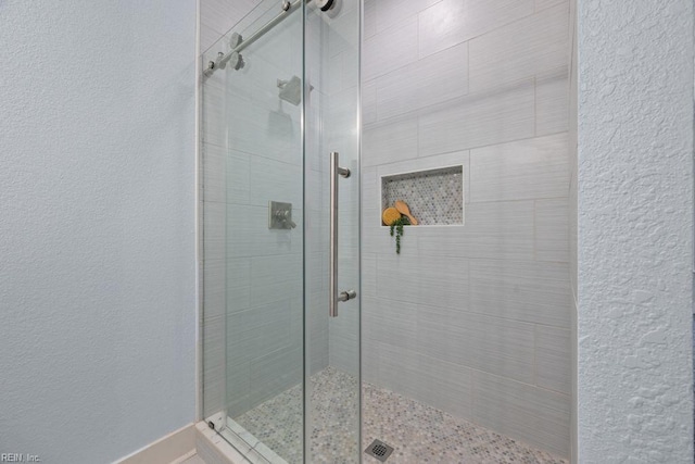 bathroom featuring a shower stall and a textured wall