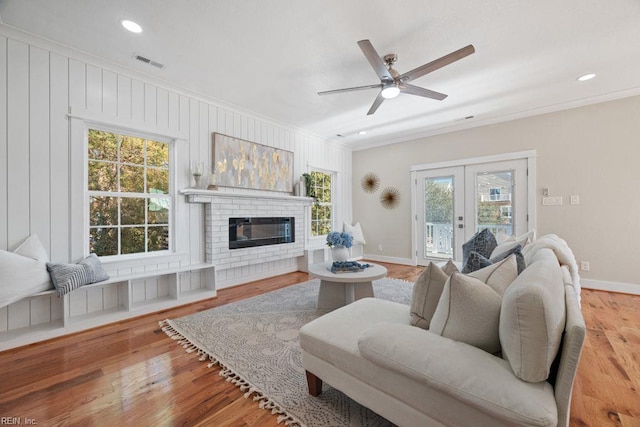 living area featuring visible vents, ornamental molding, ceiling fan, wood finished floors, and french doors